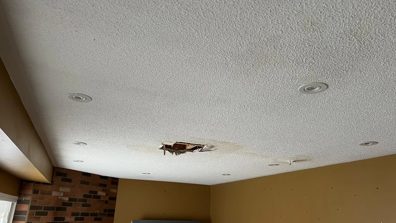 Damaged popcorn ceiling with a large hole before repair